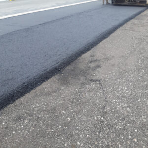 Workers paving driveway with asphalt