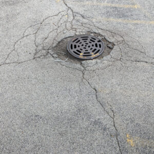 Cracked asphalt around manhole cover